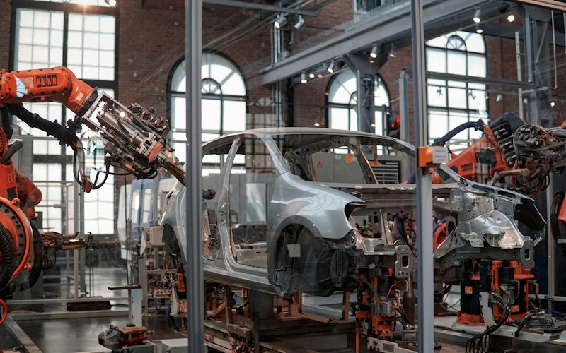 Industrial robot arms assembling vehicles on a factory line